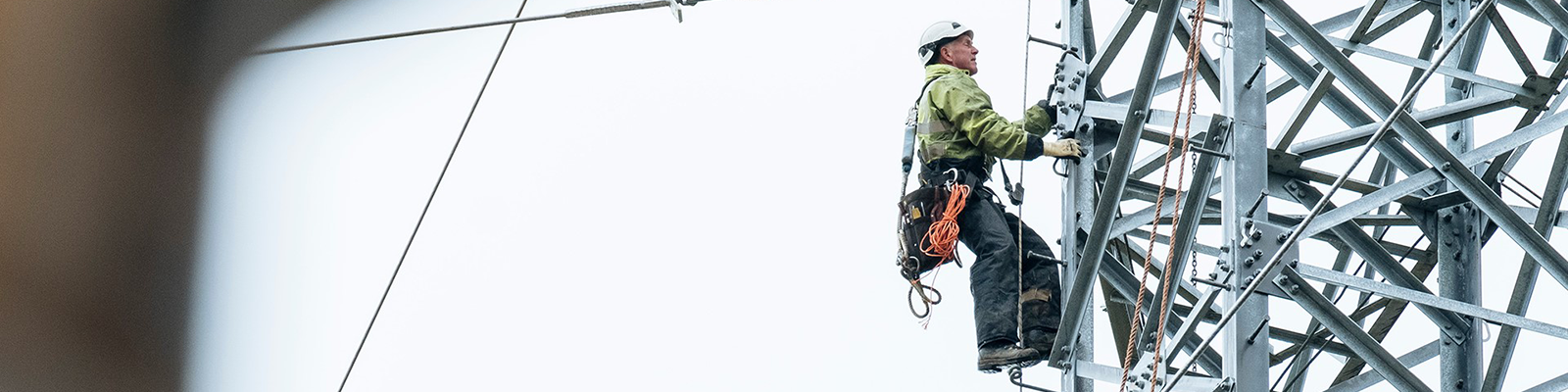 technicus die op een hoogspanningsmast klimt